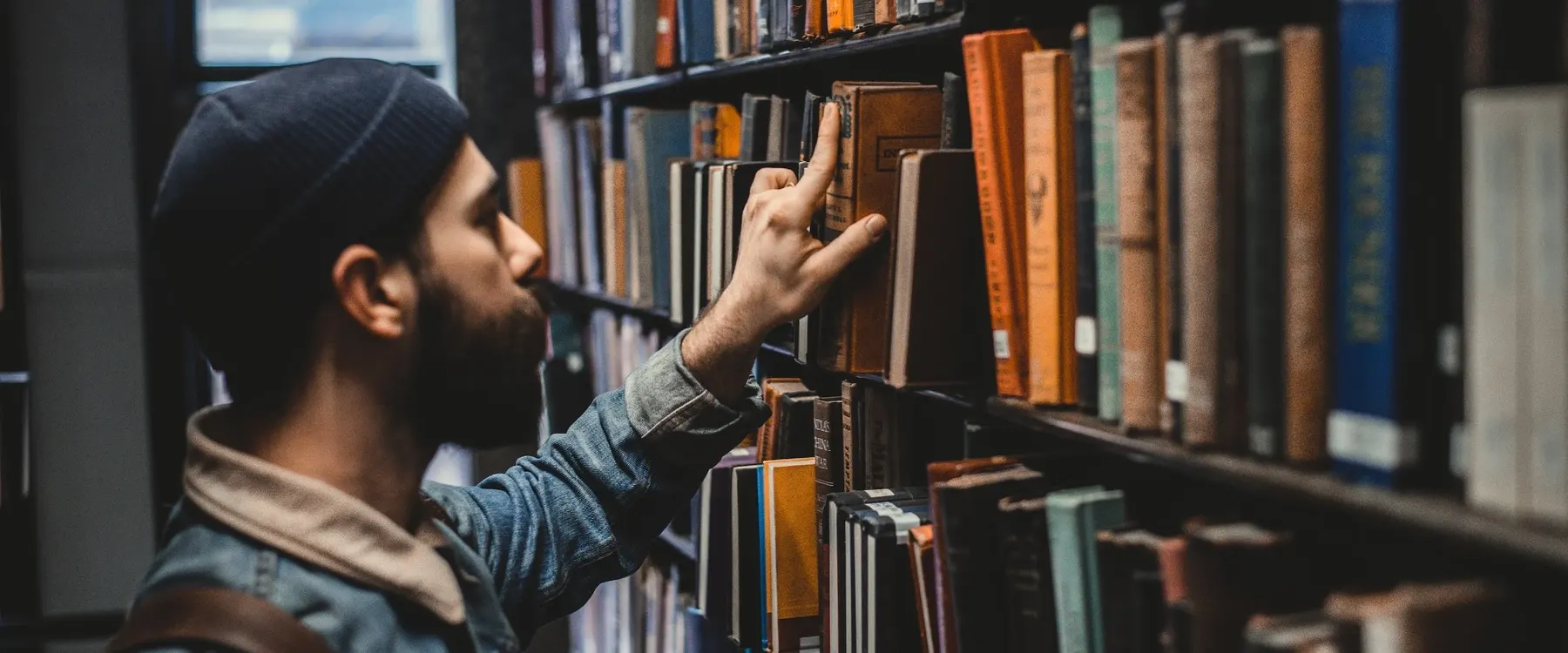 A researcher choosing a book from library shelves